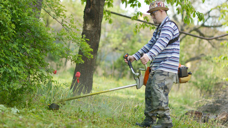 Ein Mensch mit Behinderung arbeitet in einem Park und mäht Gras