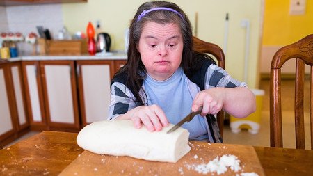Ein Frau mit Behinderung schneidet einen Teig
