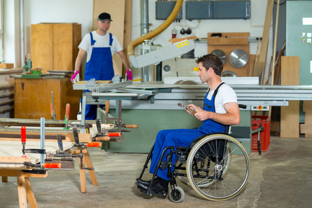 Ein Mensch im Rollstuhl arbeitet in einer Schreinerei 