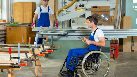 Ein Mann im Rollstuhl arbeitet in der Schreinerabteilung einer Werkstatt