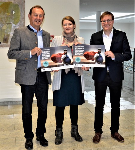 Drei Personen mit einem Plakat in der Hand